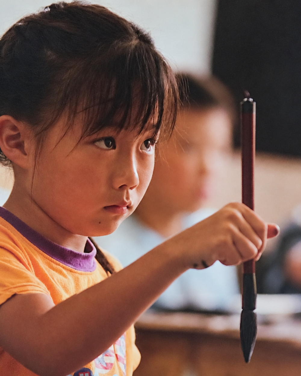 筆を持ち、一文字に集中して取り組む生徒